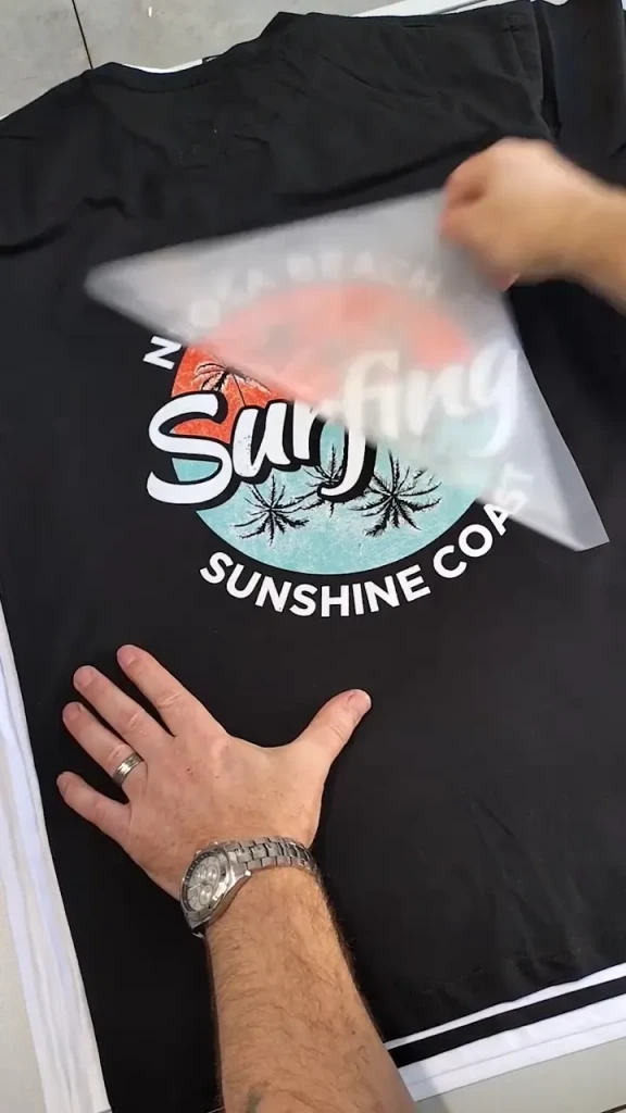 Pressing a full-colour DTF transfer onto a black tee, one step in the ZALI sportswear manufacturing process